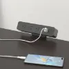 Black desktop power module with AC outlets and USB charging ports installed in a modern office desk.