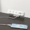 Black desktop power module with AC outlets and USB charging ports installed in a modern office desk.