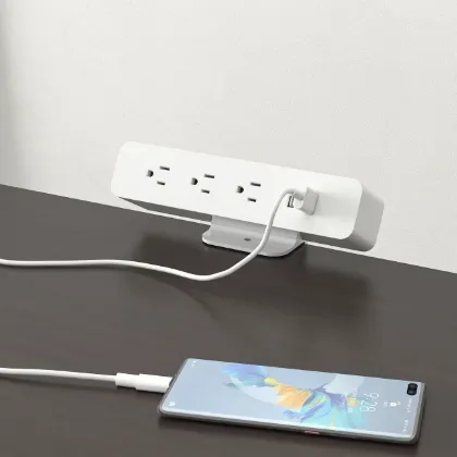 Black desktop power module with AC outlets and USB charging ports installed in a modern office desk.
