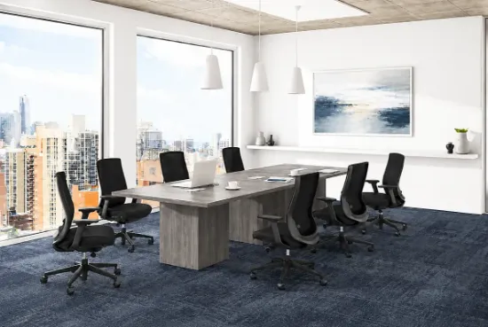 Modern commercial conference room featuring a boat-shaped conference table, ergonomic conference chairs, integrated power modules, and contemporary office design.